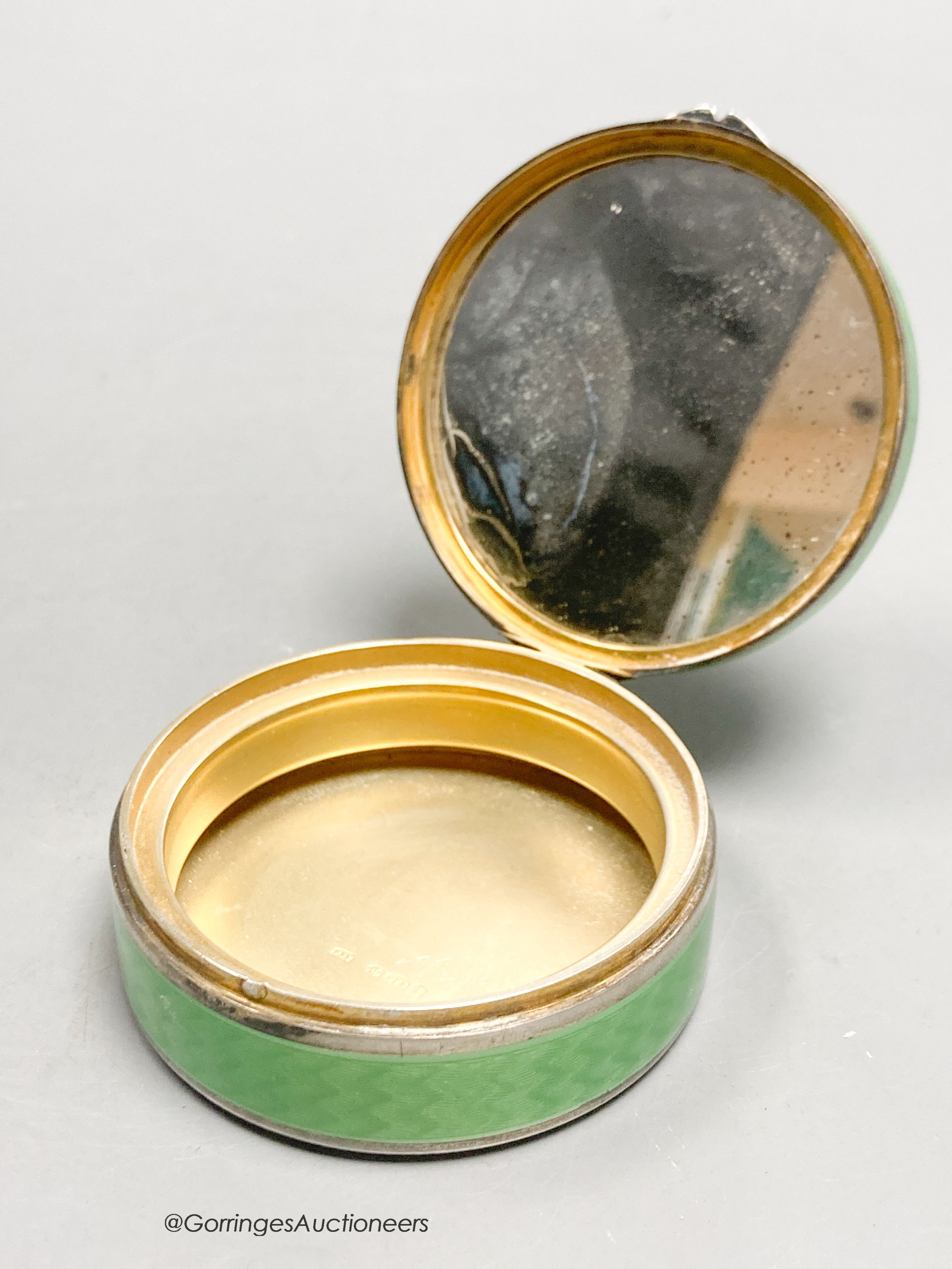 A 1920's continental silver and green guilloche enamel circular box and cover, with mirrored interior, import marks for P.H. Vogel, London, 1924, 55mm diameter by 24mm.